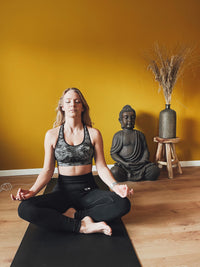 Kvinde der mediterer med korslagte ben på Earthle jordingsyogamåtten